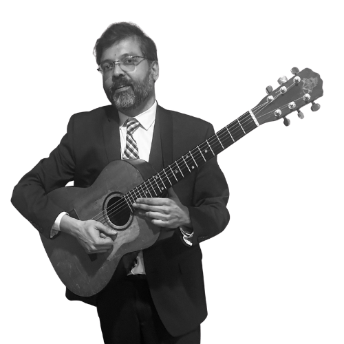 Sharat Somashekara in formal attire with an acoustic guitar